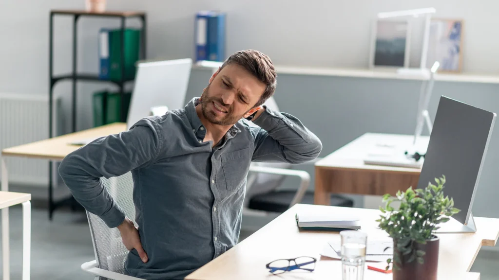 Man Stretches In Pain Sitting Down At The Office